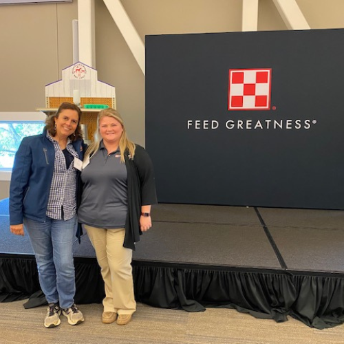 Prairieland Feeds staff standing in front of a Purina branded sign