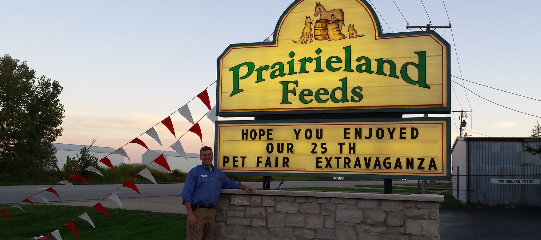 Prairieland Feeds owner in front of the roadside store sign